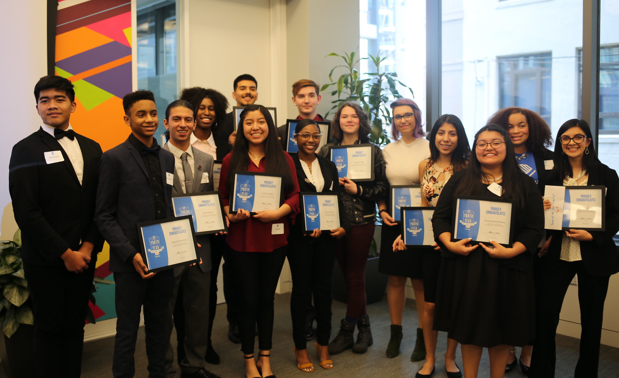 Fourteen people standing in a row holding certificates